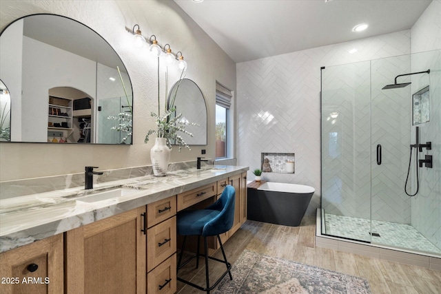 full bath with a sink, tile walls, a soaking tub, a shower stall, and double vanity