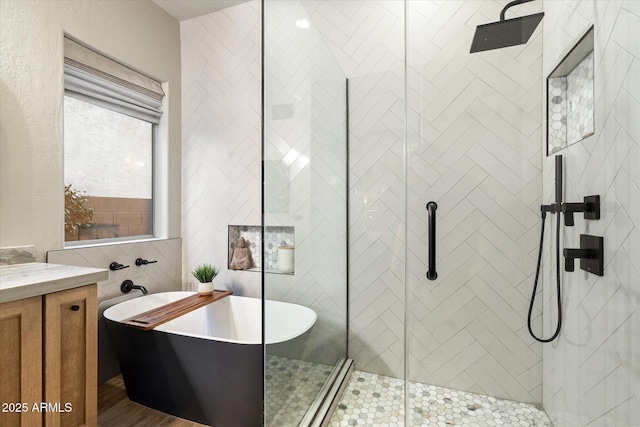 bathroom with a freestanding bath, a shower stall, vanity, and tile walls