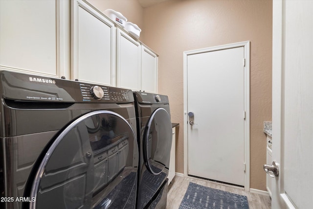 washroom featuring light wood-style floors, washer and dryer, cabinet space, and baseboards