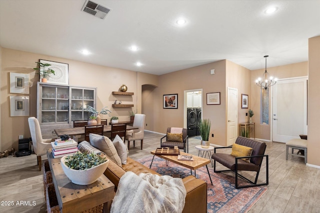 living area with light wood-type flooring, visible vents, arched walkways, and independent washer and dryer