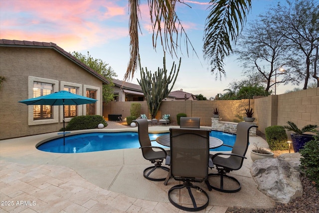 pool at dusk featuring a patio area, a fenced backyard, a fenced in pool, and outdoor dining space