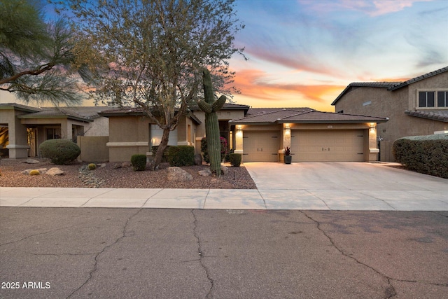 view of front of house with a garage, concrete driveway, a tile roof, and stucco siding