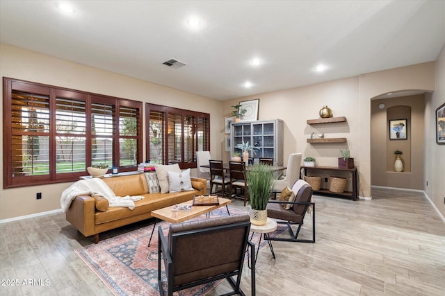 living room featuring visible vents, arched walkways, baseboards, light wood-style flooring, and recessed lighting