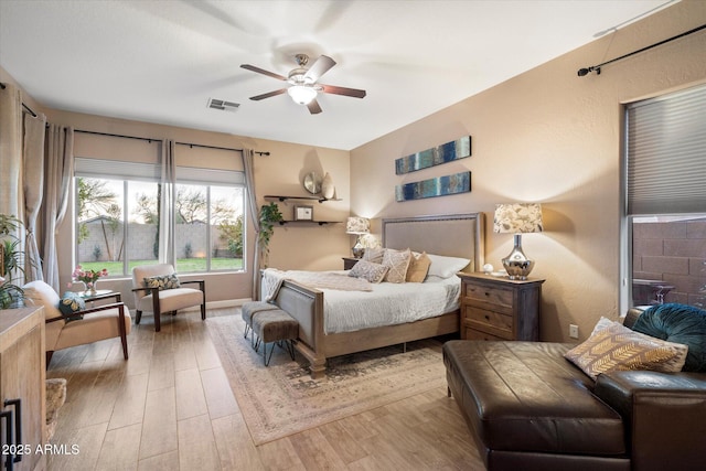 bedroom featuring a ceiling fan, visible vents, and wood finished floors