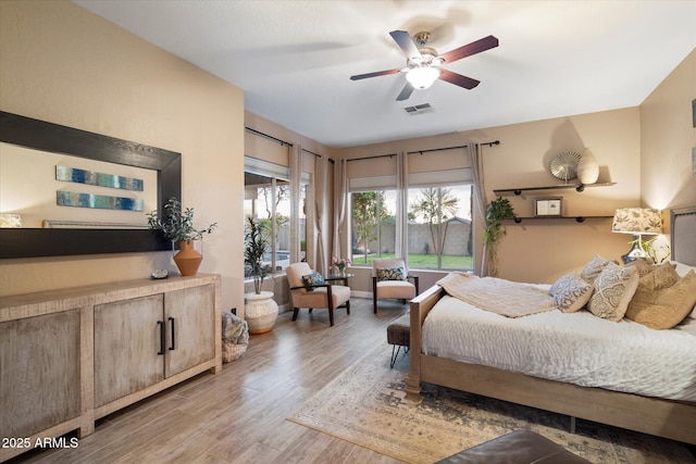 bedroom featuring light wood-style floors, visible vents, and a ceiling fan