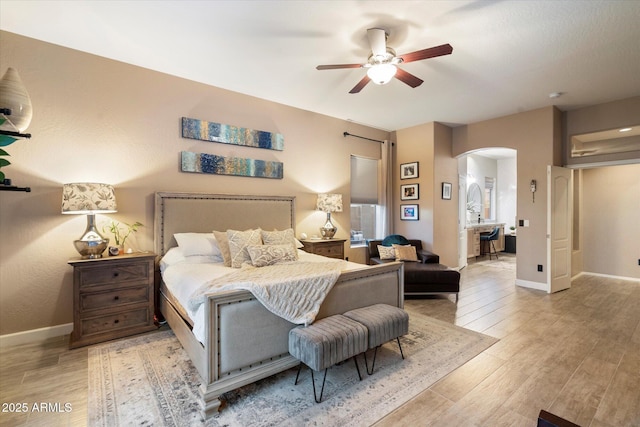 bedroom with baseboards, arched walkways, ceiling fan, and wood finished floors