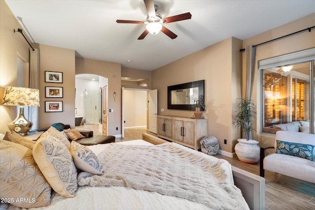 bedroom featuring arched walkways, ceiling fan, baseboards, and wood finished floors