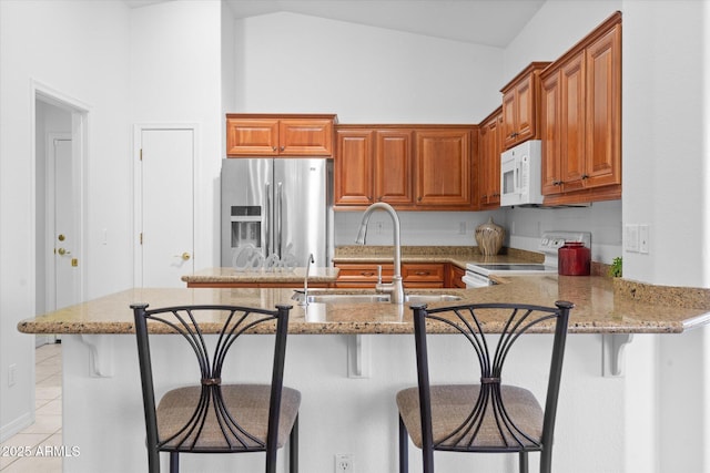 4976 S Sugarberry Ln, Gilbert, AZ 85298 - kitchen with white appliances, light stone counters, light tile patterned floors, a peninsula, and brown cabinetry