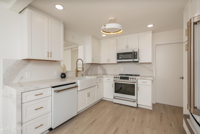 kitchen featuring white cabinetry, sink, white appliances, and light wood-type flooring