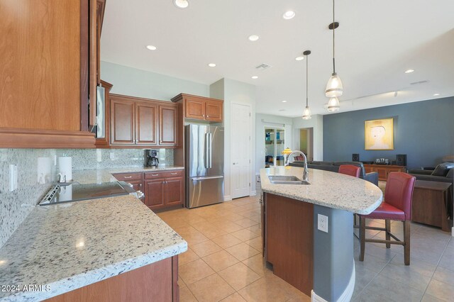 kitchen with sink, a kitchen bar, stainless steel appliances, and an island with sink