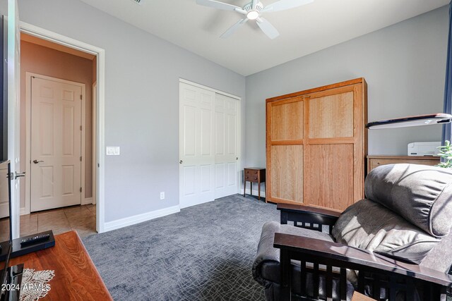 sitting room with ceiling fan and dark colored carpet