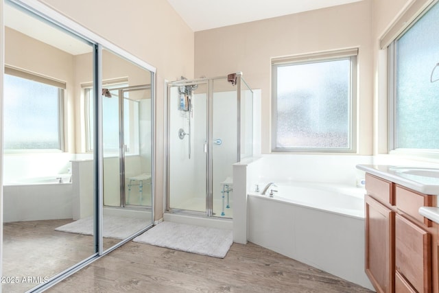 bathroom with vanity, wood-type flooring, plenty of natural light, and independent shower and bath