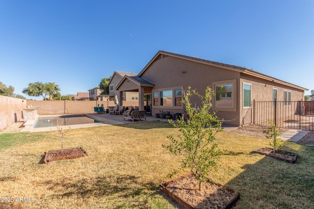 back of property with a patio area, a fenced in pool, and a yard