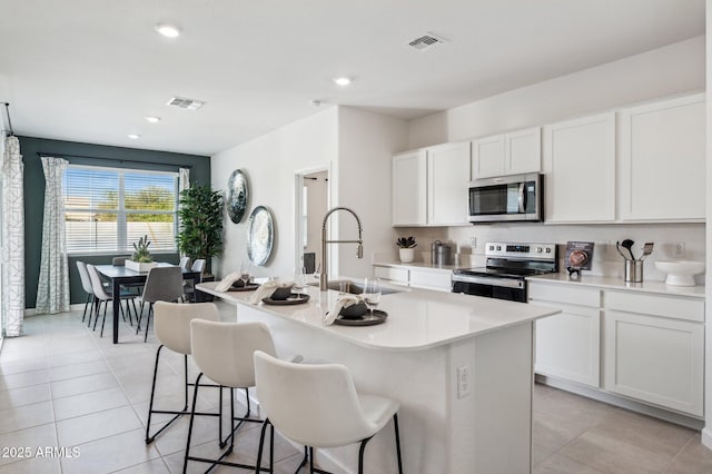 1584 S 241st Ave, Buckeye, AZ 85326 - kitchen featuring appliances with stainless steel finishes, light countertops, a center island with sink, a kitchen bar, and white cabinets