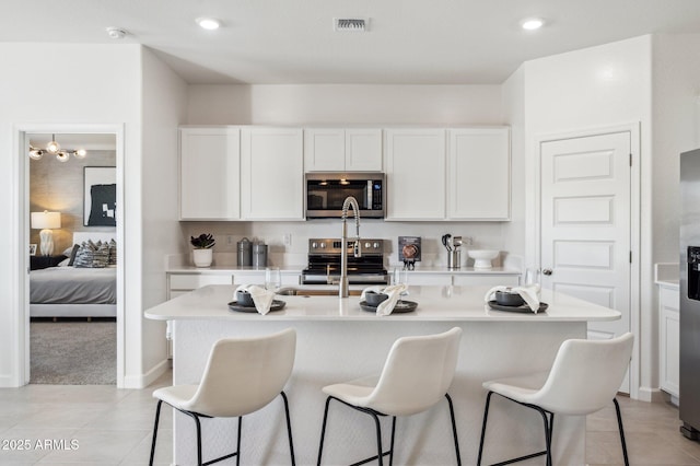 1584 S 241st Ave, Buckeye, AZ 85326 - kitchen with stainless steel appliances, a breakfast bar, light countertops, white cabinets, and recessed lighting