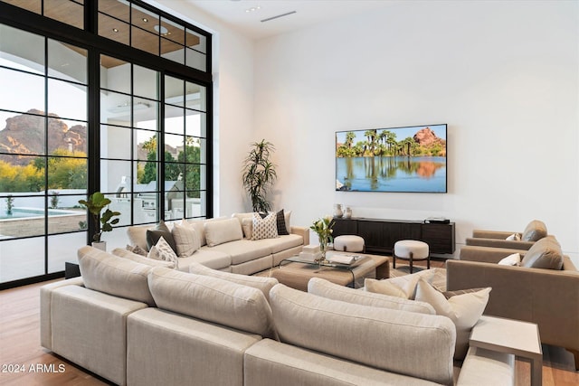 living room featuring a mountain view, a wall of windows, wood-type flooring, and a high ceiling