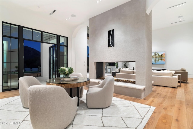 dining space featuring light wood-type flooring and a towering ceiling