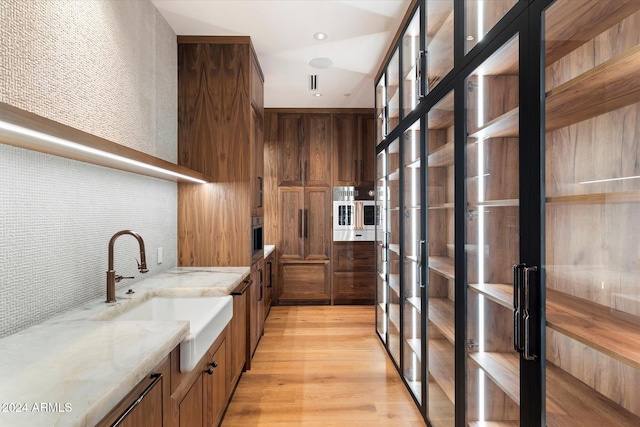 bar with tasteful backsplash, a sink, light wood-style flooring, and recessed lighting