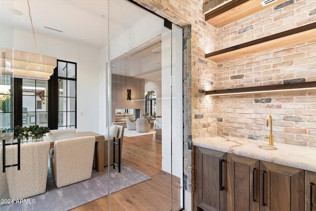 dining area with light hardwood / wood-style flooring, bar, and brick wall