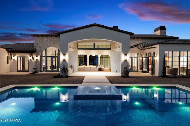 rear view of property with french doors, a chimney, a patio area, and stucco siding