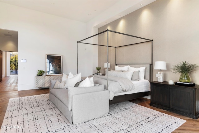 bedroom featuring a towering ceiling and light hardwood / wood-style flooring