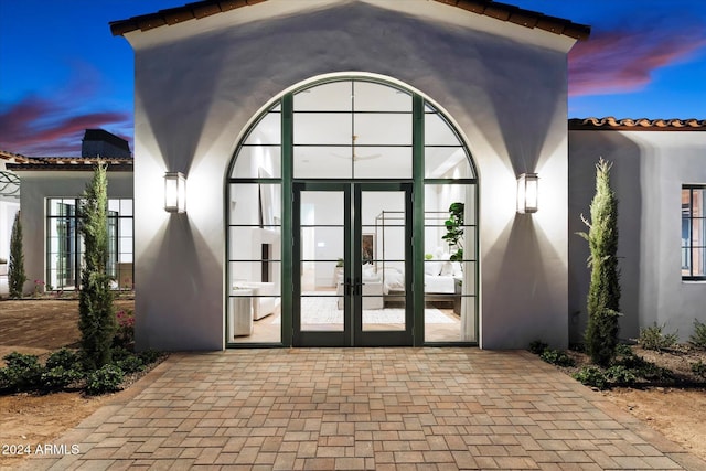 doorway to property featuring french doors, a tile roof, and stucco siding