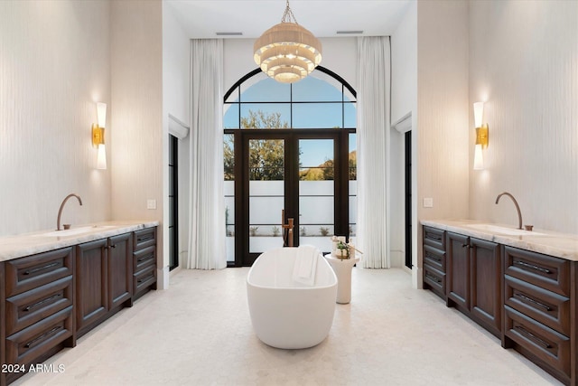 bathroom featuring a bathtub, a towering ceiling, vanity, and an inviting chandelier