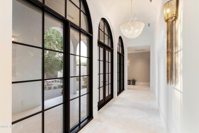 corridor with a towering ceiling, french doors, and a chandelier