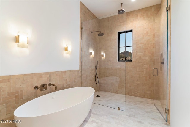 bathroom featuring a stall shower, a wainscoted wall, tile walls, and a soaking tub