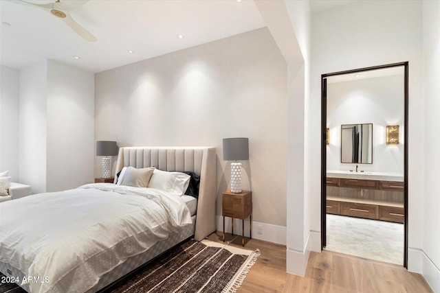 bedroom featuring light wood-style floors, baseboards, and ensuite bathroom