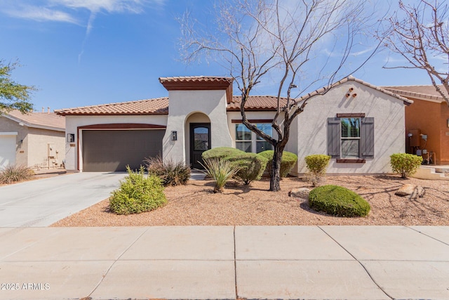 mediterranean / spanish-style home with a tiled roof, an attached garage, driveway, and stucco siding