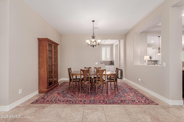 tiled dining space featuring baseboards and a chandelier