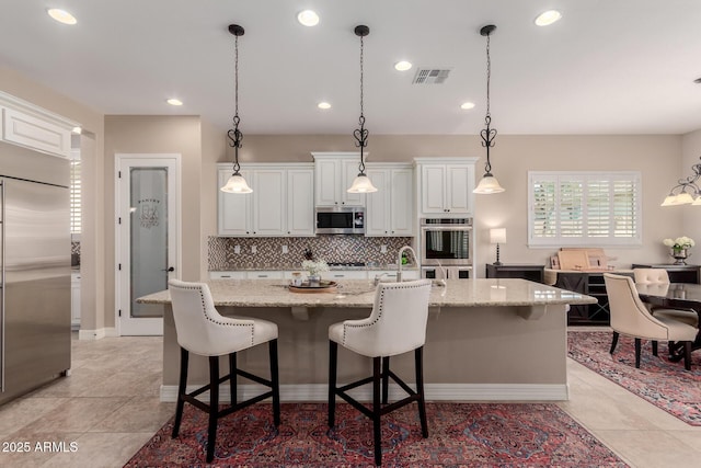 kitchen with visible vents, backsplash, appliances with stainless steel finishes, light tile patterned flooring, and white cabinets