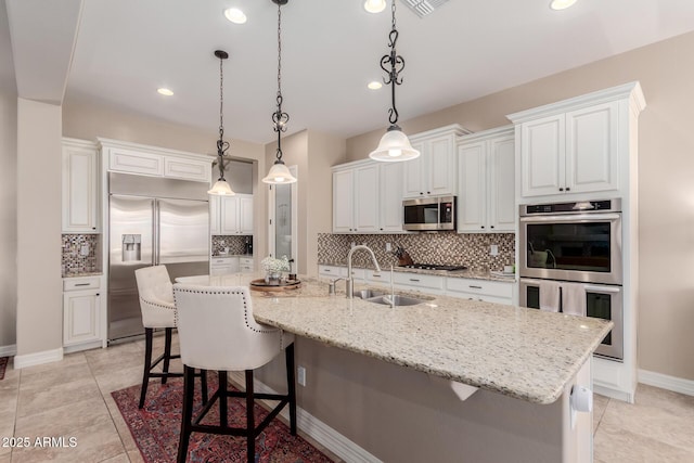 kitchen with a spacious island, a sink, appliances with stainless steel finishes, white cabinetry, and tasteful backsplash