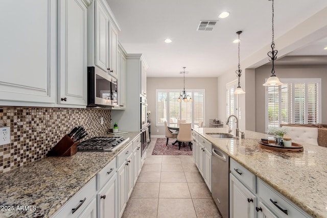 kitchen with visible vents, light tile patterned flooring, a sink, decorative backsplash, and stainless steel appliances