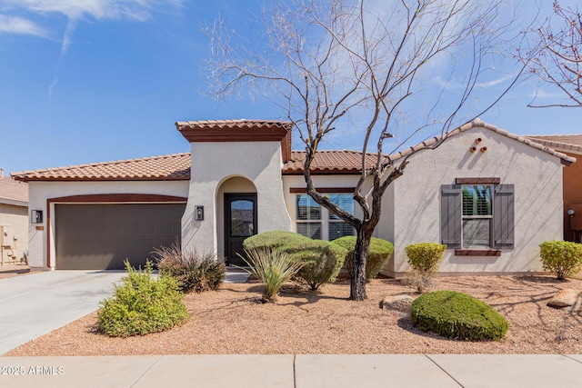 mediterranean / spanish house featuring a tiled roof, stucco siding, an attached garage, and concrete driveway