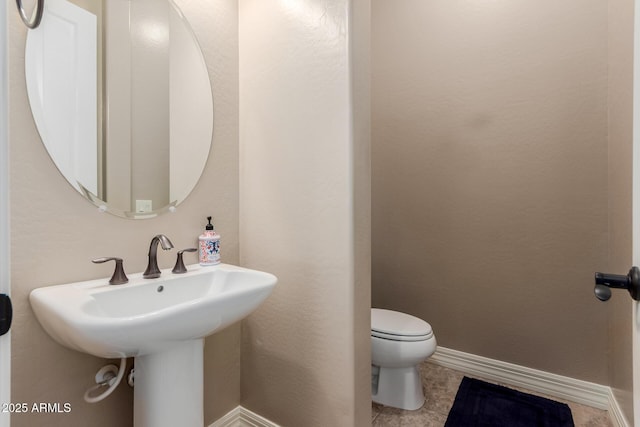 half bath featuring a sink, baseboards, and toilet