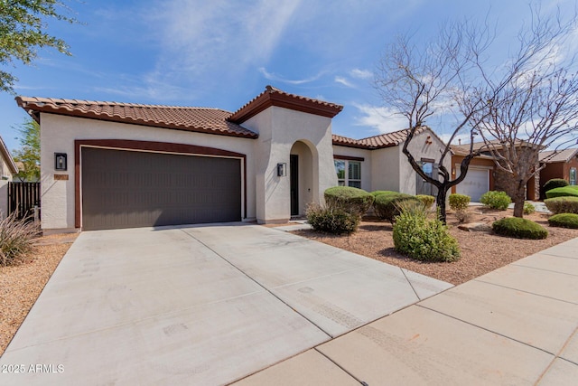 mediterranean / spanish home with stucco siding, driveway, an attached garage, and a tiled roof