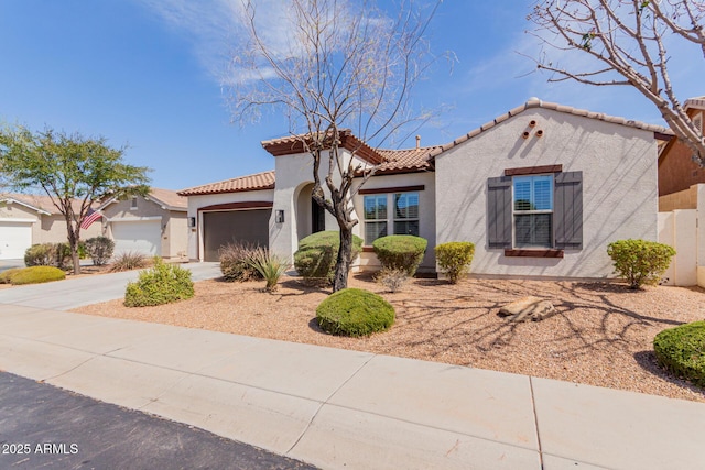 mediterranean / spanish house featuring a tile roof, concrete driveway, an attached garage, and stucco siding