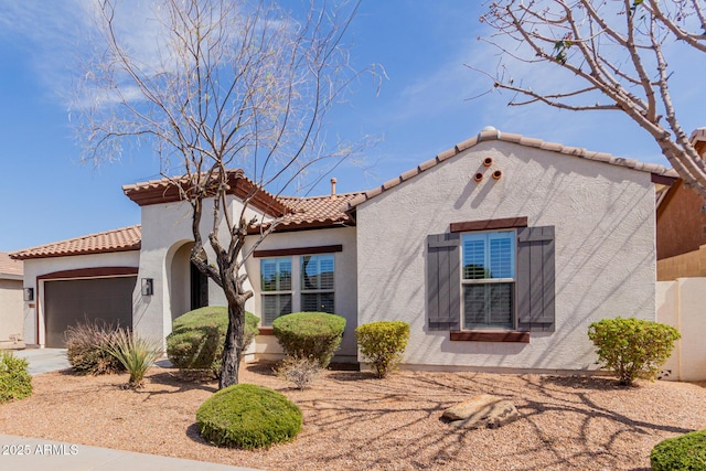 mediterranean / spanish home featuring a tiled roof, a garage, driveway, and stucco siding