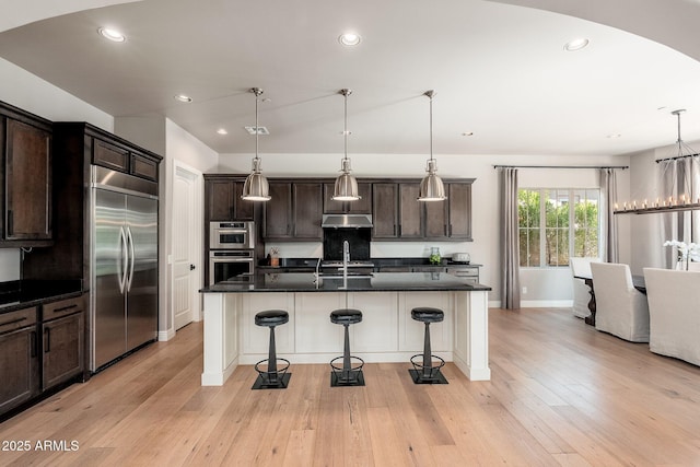 11070 E Bent Tree Dr, Scottsdale, AZ 85262 - kitchen with appliances with stainless steel finishes, dark countertops, a breakfast bar, dark brown cabinetry, and recessed lighting