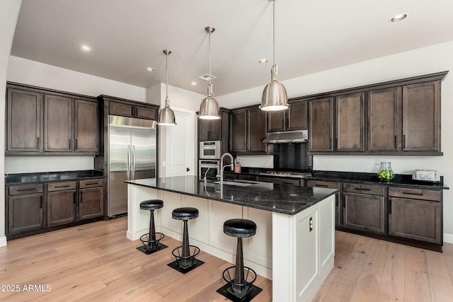 11070 E Bent Tree Dr, Scottsdale, AZ 85262 - kitchen with stainless steel appliances, dark brown cabinets, a kitchen breakfast bar, light wood-style flooring, and recessed lighting