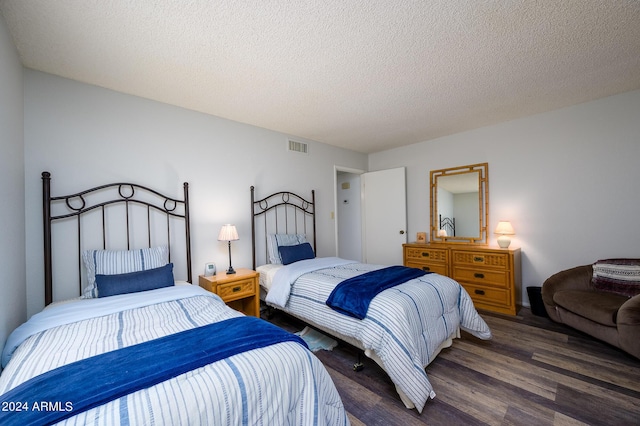 bedroom featuring a textured ceiling, dark wood-type flooring, and visible vents