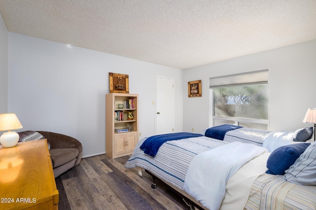 bedroom featuring dark wood-style floors, a textured ceiling, and baseboards