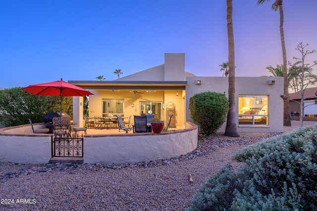 rear view of house with a ceiling fan, a patio, and stucco siding