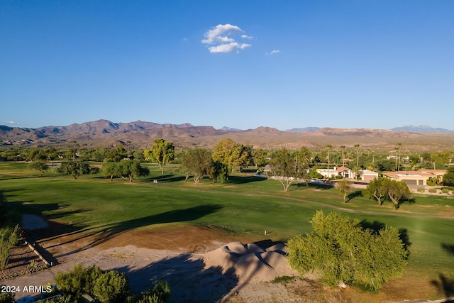 view of property's community with view of golf course, a mountain view, and a lawn