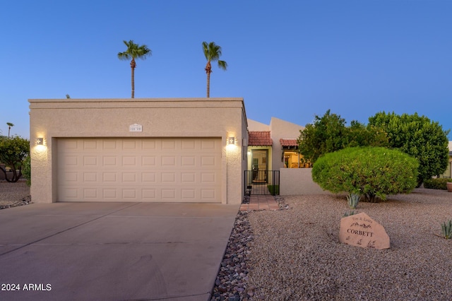 southwest-style home featuring driveway, a garage, a tiled roof, a gate, and stucco siding