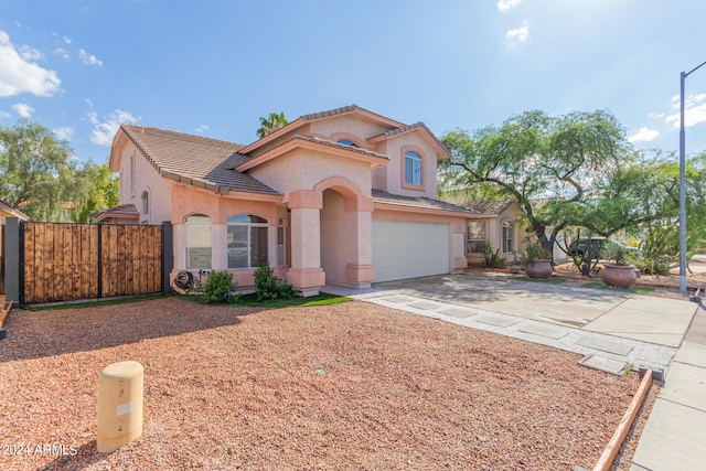 mediterranean / spanish house featuring stucco siding, concrete driveway, an attached garage, fence, and a tiled roof