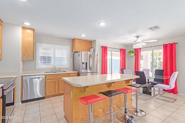 kitchen featuring stainless steel appliances, a sink, visible vents, a kitchen breakfast bar, and light countertops