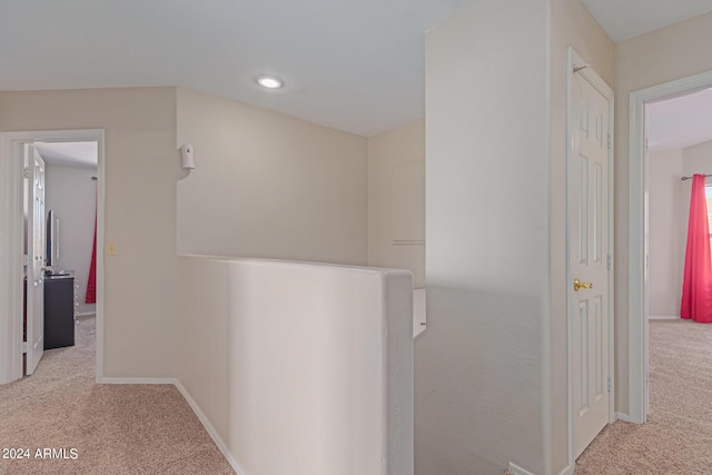 corridor with carpet, baseboards, and an upstairs landing